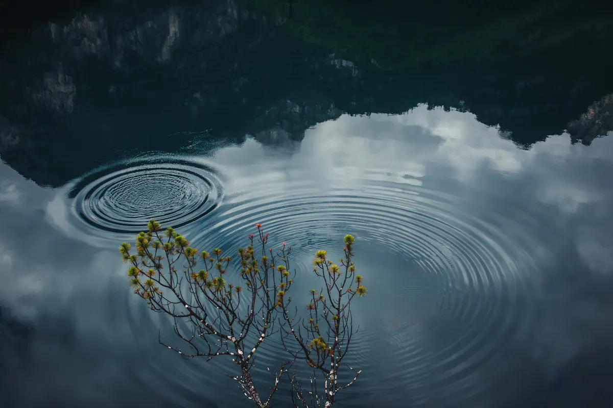 Serene lake scene in Sospirolo, Italy, capturing ripples and cloud reflections.