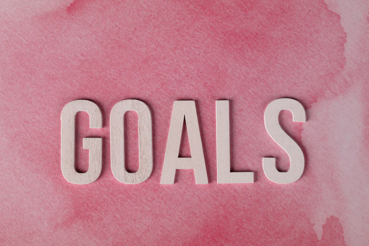 Motivational word 'GOALS' on a pink watercolor background for inspiration.