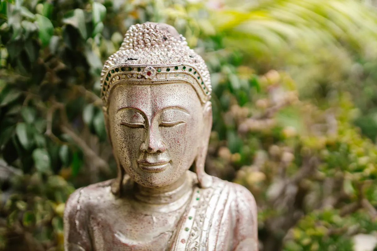 Serene Buddha statue adorned with gems in a lush garden setting.