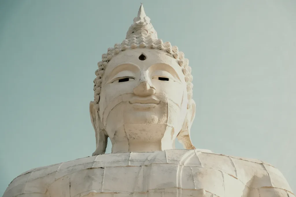 A majestic view of a large Buddha statue with a serene expression under a clear sky.