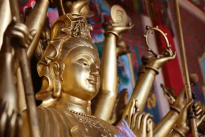 Close-up of a golden Buddhist statue with intricate details at a temple.