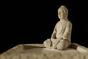 Serene Buddha statue sitting in zen meditation on fine sand, embodying tranquility.